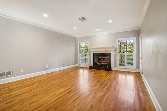 unfurnished living room featuring a tiled fireplace, crown molding, and wood-type flooring