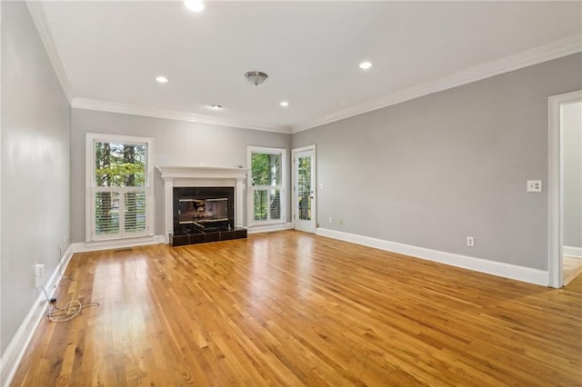 unfurnished living room featuring light hardwood / wood-style floors, crown molding, and a tile fireplace