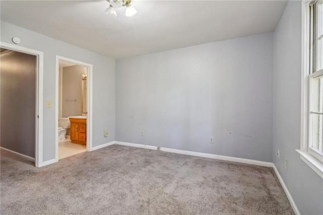 unfurnished bedroom featuring light colored carpet and ensuite bath