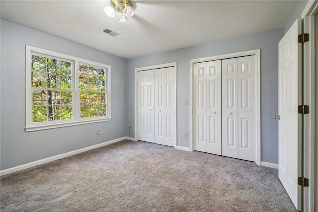 unfurnished bedroom featuring carpet flooring and two closets