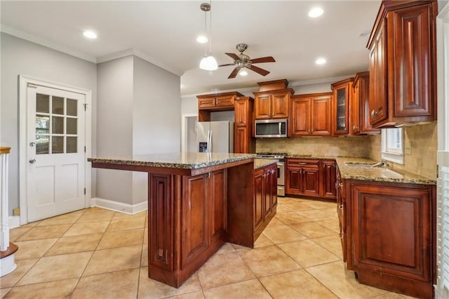 kitchen featuring ceiling fan, light stone counters, appliances with stainless steel finishes, a kitchen island, and ornamental molding