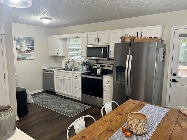 kitchen featuring stainless steel appliances, a textured ceiling, sink, white cabinets, and dark wood-type flooring