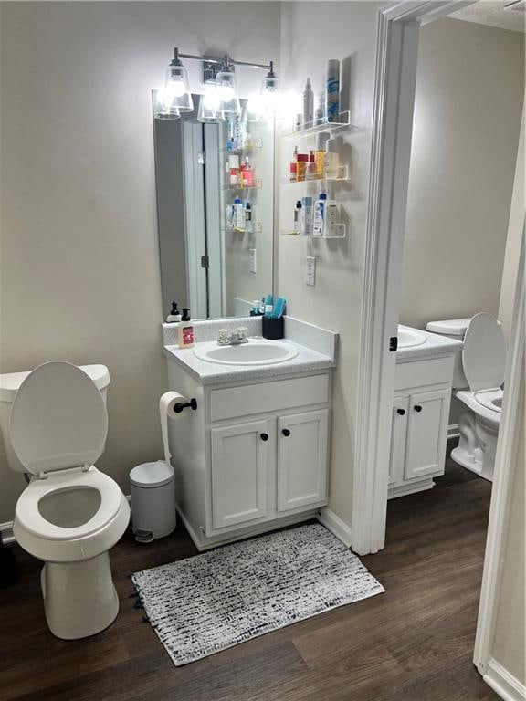 bathroom with toilet, vanity, and wood-type flooring