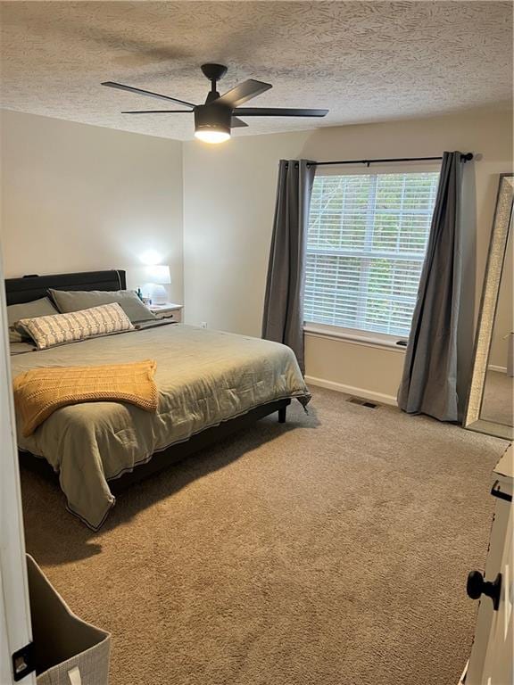 carpeted bedroom with ceiling fan and a textured ceiling