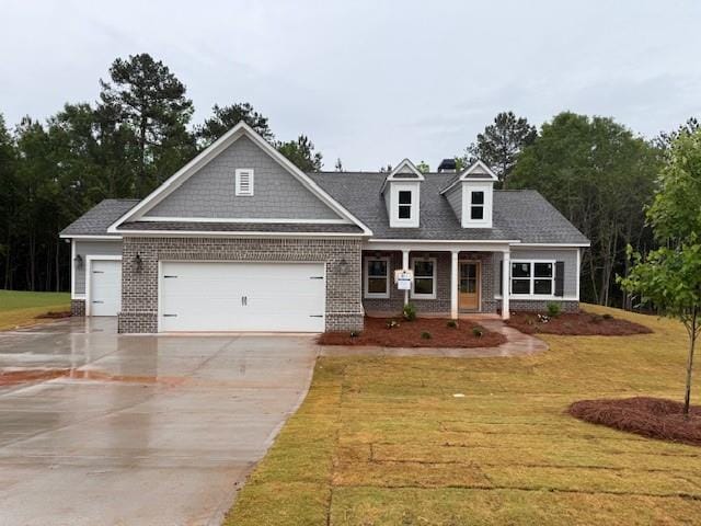 view of front of property with brick siding, an attached garage, driveway, and a front lawn
