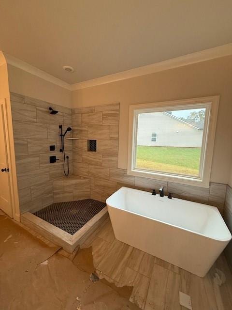 full bath with tile walls, a shower stall, a soaking tub, and ornamental molding
