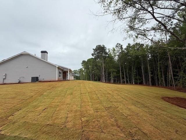 view of green lawn with central AC