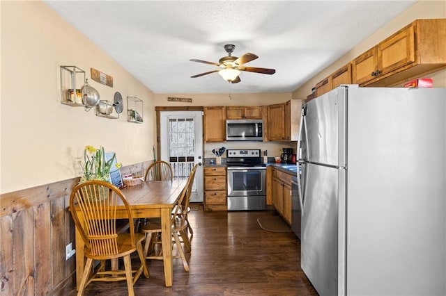 kitchen with appliances with stainless steel finishes, dark wood-type flooring, a textured ceiling, and ceiling fan