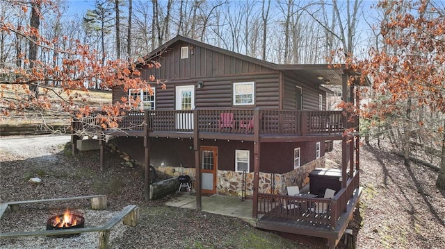 back of property with a wooden deck, a patio area, and a fire pit