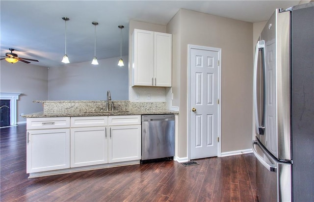 kitchen with appliances with stainless steel finishes, decorative light fixtures, white cabinetry, sink, and backsplash