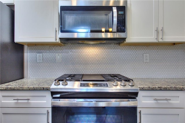 kitchen featuring tasteful backsplash, light stone countertops, stainless steel appliances, and white cabinetry