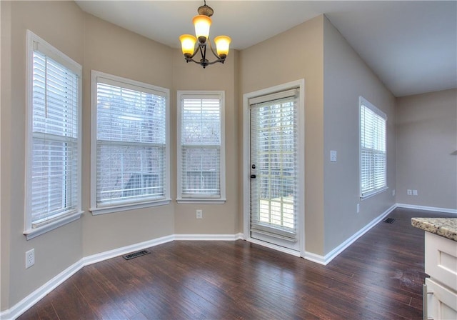 entryway with dark wood-type flooring and an inviting chandelier