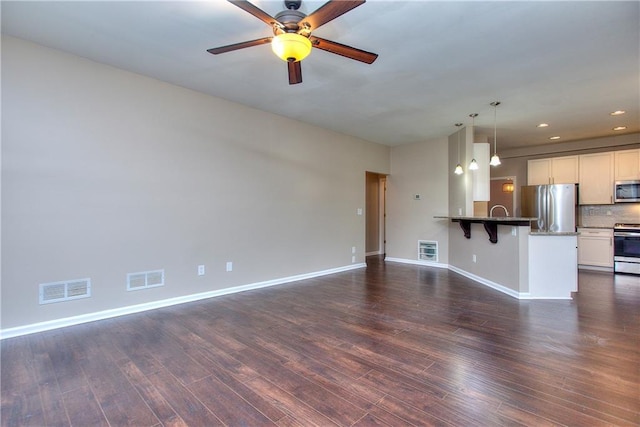 unfurnished living room featuring ceiling fan, dark hardwood / wood-style floors, and sink