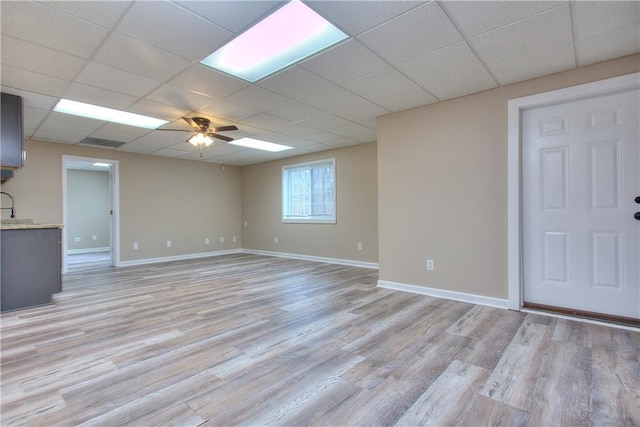 unfurnished living room with ceiling fan, light hardwood / wood-style floors, and a drop ceiling