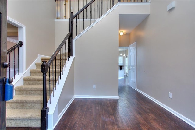 stairway featuring a towering ceiling and hardwood / wood-style floors