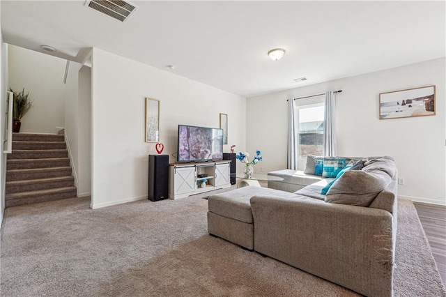 living room featuring stairway, carpet flooring, visible vents, and baseboards