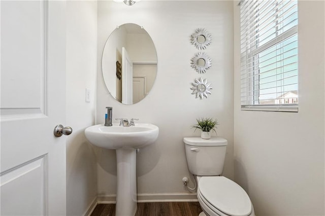 bathroom with toilet, a sink, baseboards, and wood finished floors