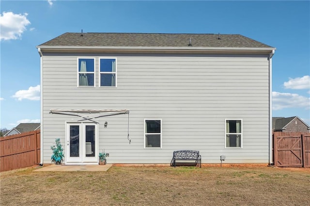 back of house featuring a yard, a fenced backyard, and a gate