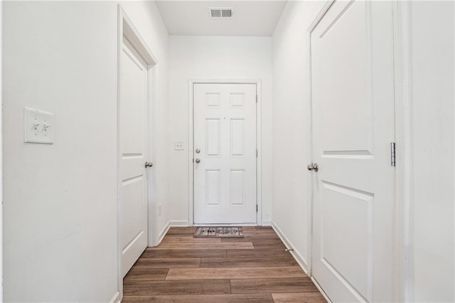 corridor with baseboards, visible vents, and wood finished floors