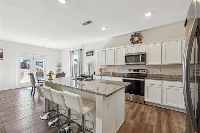 kitchen with appliances with stainless steel finishes, visible vents, a sink, and wood finished floors