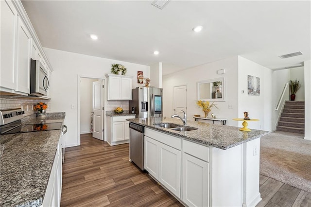 kitchen featuring wood finished floors, a sink, white cabinetry, appliances with stainless steel finishes, and backsplash