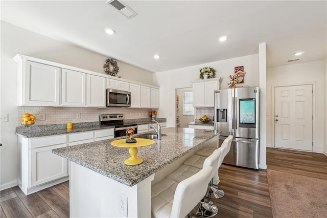 kitchen with stainless steel appliances, dark wood-style flooring, a sink, and white cabinetry