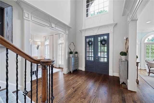 entryway with a towering ceiling, french doors, dark hardwood / wood-style flooring, and crown molding