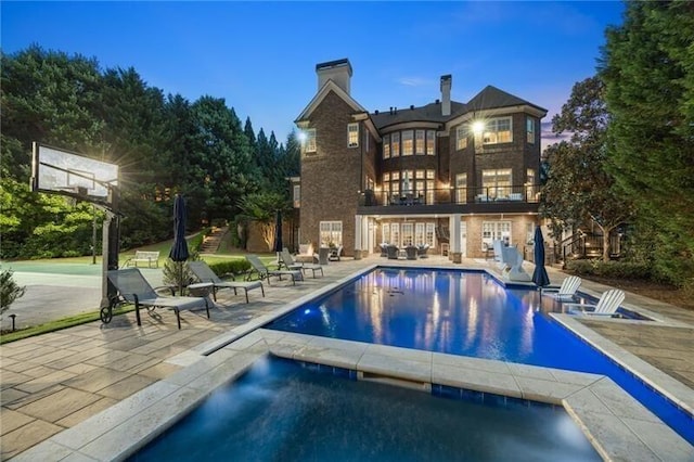 pool at dusk with a patio area