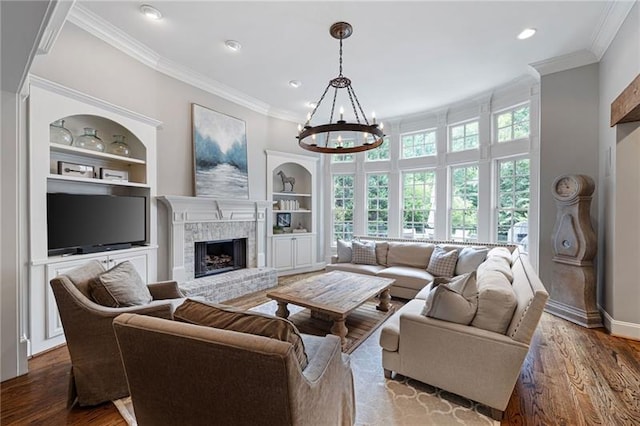 living room featuring a fireplace, a chandelier, built in shelves, and wood-type flooring