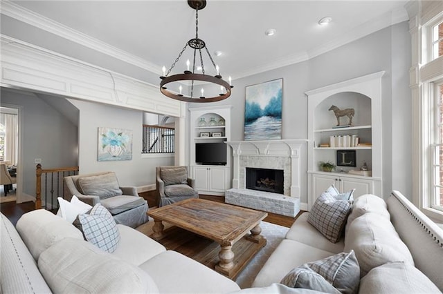 living room featuring a brick fireplace, hardwood / wood-style floors, built in features, and plenty of natural light