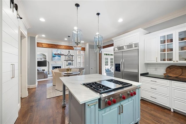 kitchen with a kitchen island, a barn door, blue cabinetry, white cabinets, and appliances with stainless steel finishes