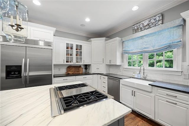 kitchen featuring sink, white cabinets, ornamental molding, hanging light fixtures, and appliances with stainless steel finishes