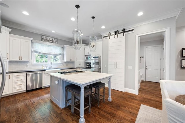 kitchen with white cabinets, hanging light fixtures, a barn door, and appliances with stainless steel finishes