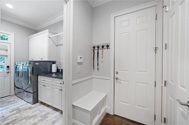 clothes washing area with sink, cabinets, light hardwood / wood-style flooring, washing machine and dryer, and crown molding