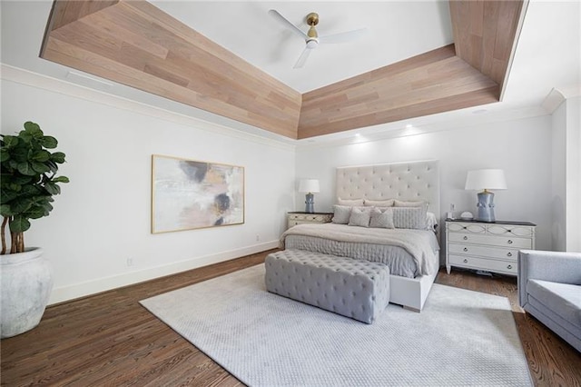 bedroom featuring dark wood-type flooring, ceiling fan, a tray ceiling, and ornamental molding