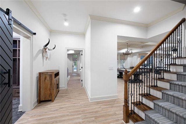 entrance foyer featuring coffered ceiling, a barn door, light wood-type flooring, beamed ceiling, and an inviting chandelier