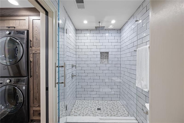 bathroom featuring a shower with door and stacked washer / dryer