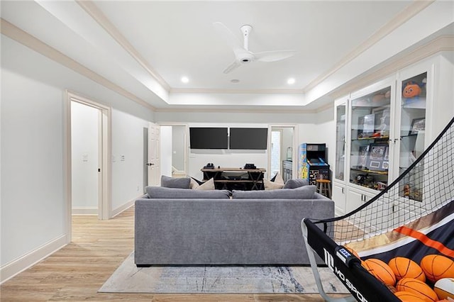 living room with crown molding, ceiling fan, a tray ceiling, and light hardwood / wood-style flooring