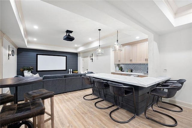 kitchen with a raised ceiling, light hardwood / wood-style floors, a breakfast bar, and decorative backsplash