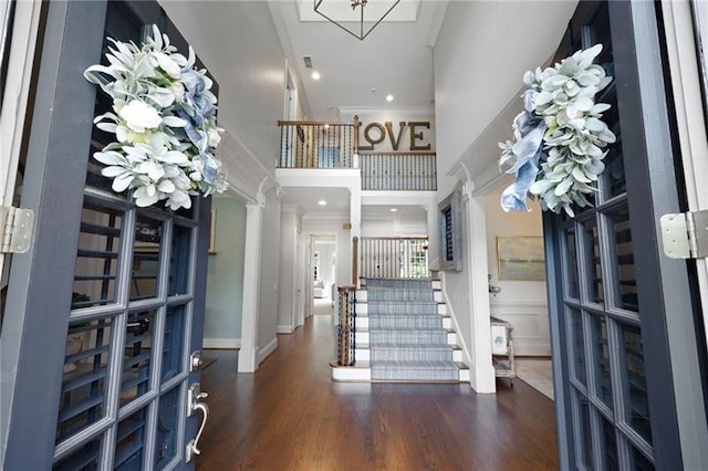 entrance foyer featuring a high ceiling, crown molding, and dark hardwood / wood-style floors