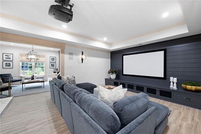 home theater room with light hardwood / wood-style floors and a tray ceiling