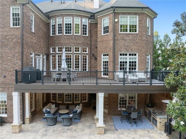 back of property with exterior kitchen, a patio, and a wooden deck