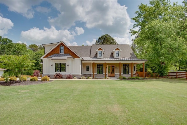 modern inspired farmhouse featuring fence, covered porch, a front yard, and a standing seam roof