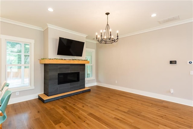 unfurnished living room featuring visible vents, baseboards, an inviting chandelier, ornamental molding, and light wood-style flooring
