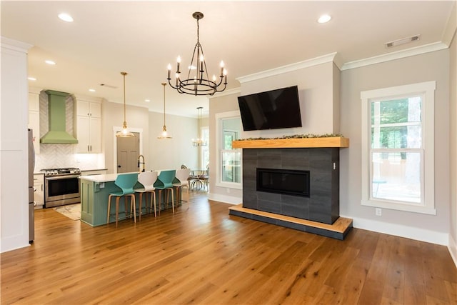 living area with visible vents, light wood-type flooring, a notable chandelier, ornamental molding, and recessed lighting