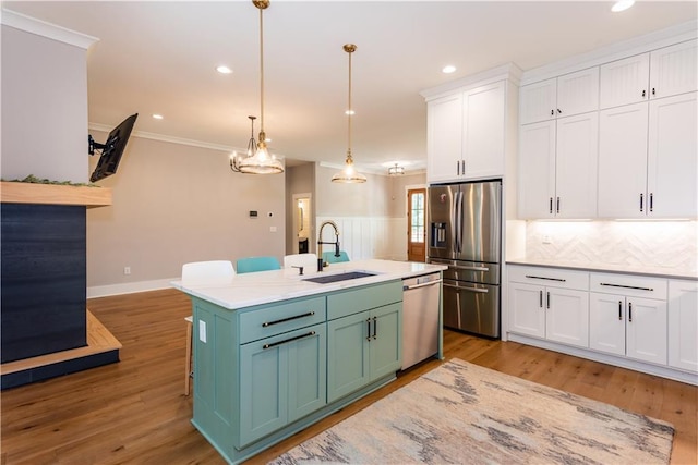 kitchen with crown molding, a sink, stainless steel appliances, white cabinetry, and tasteful backsplash