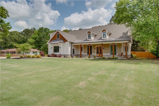 view of front of house with a front lawn, board and batten siding, fence, and covered porch