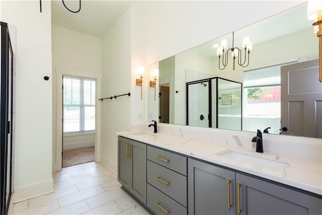 bathroom featuring baseboards, a notable chandelier, a shower stall, and a sink