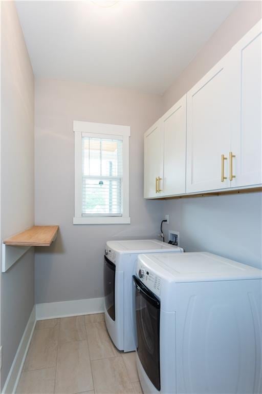 laundry room with separate washer and dryer, cabinet space, light tile patterned floors, and baseboards