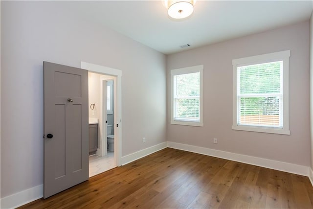 unfurnished room featuring baseboards, visible vents, and hardwood / wood-style floors